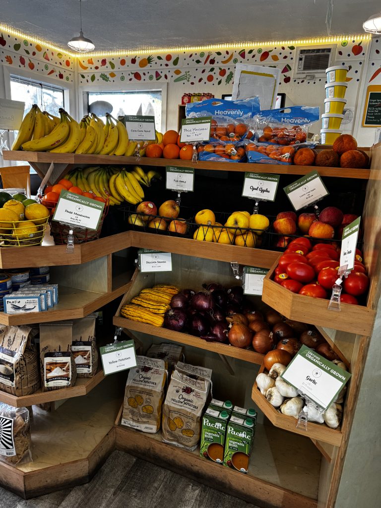 A custom wood display shelf in a neighborhood market features fresh, seasonal produce for sale.