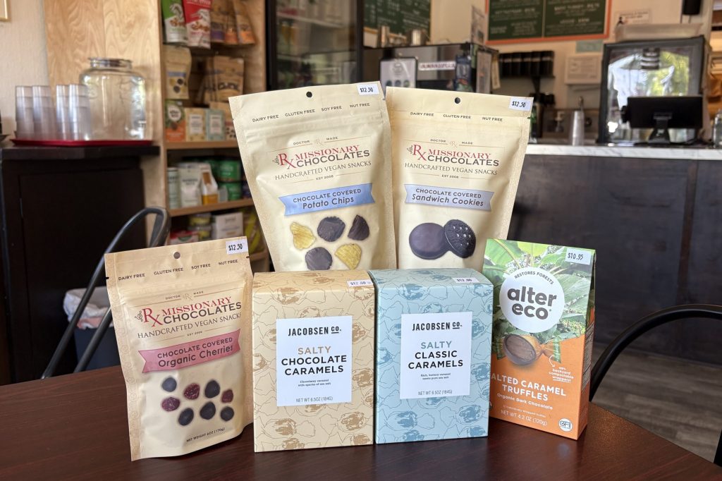 A collection of packages of sweets, chocolates, and caramels is arranged on a dark wood table.